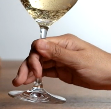 Hold a stemmed glass by the stem with two fingers